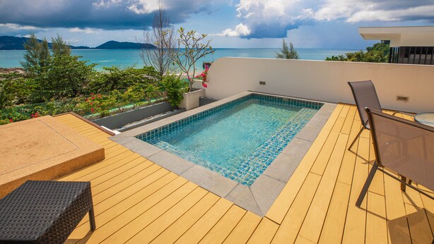 Una piscina al terrat amb vista a l'oceà, un solàrium de fusta i mobiliari exterior.