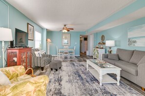 A living room with a ceiling fan, a dining area with a table and chairs, a sofa, a coffee table, and a cabinet.