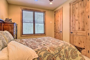 A bedroom with a bed, a dresser, a window with blinds, and wooden doors. - Lakefront Retreat at Giants Ridge: Golf, Hike, Ski (Biwabik)