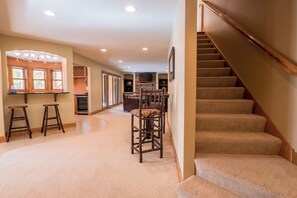 A spacious hallway with a carpeted floor, a dining area with wooden chairs, and a staircase with carpeted steps. - Lakefront Retreat at Giants Ridge: Golf, Hike, Ski (Biwabik)
