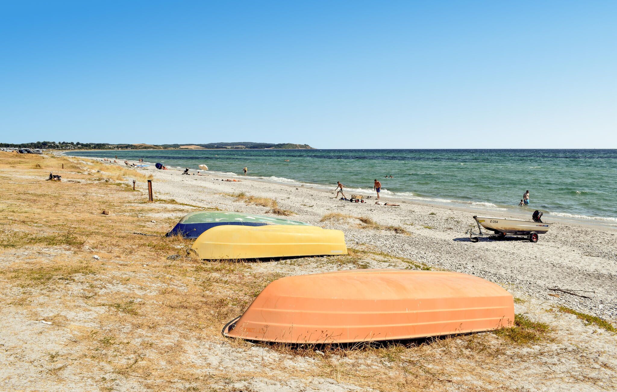 A beach with several boats and people.