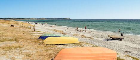 A beach with several boats and people.