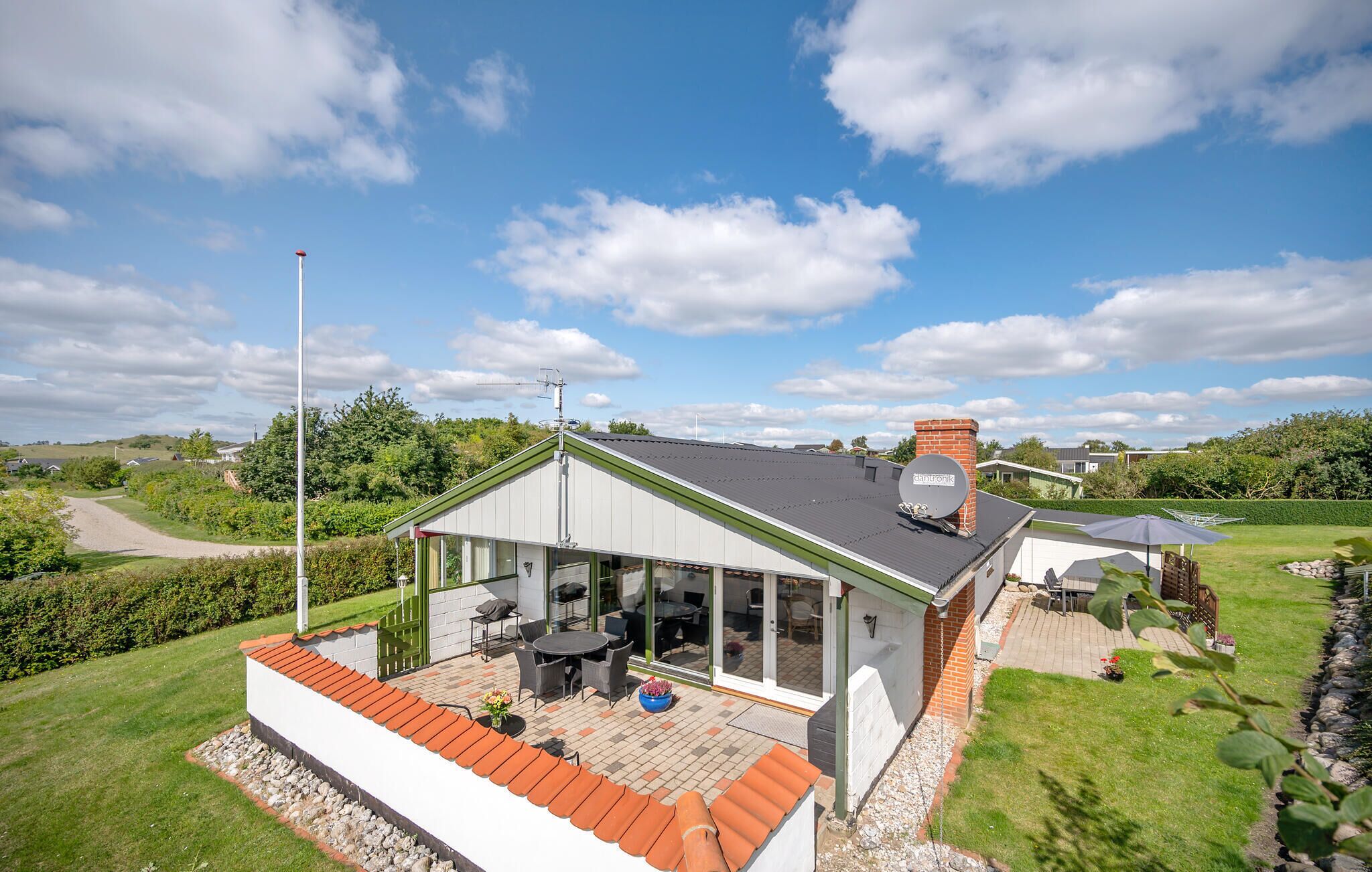A modern house with a patio, a satellite dish, and a view of the surrounding landscape.