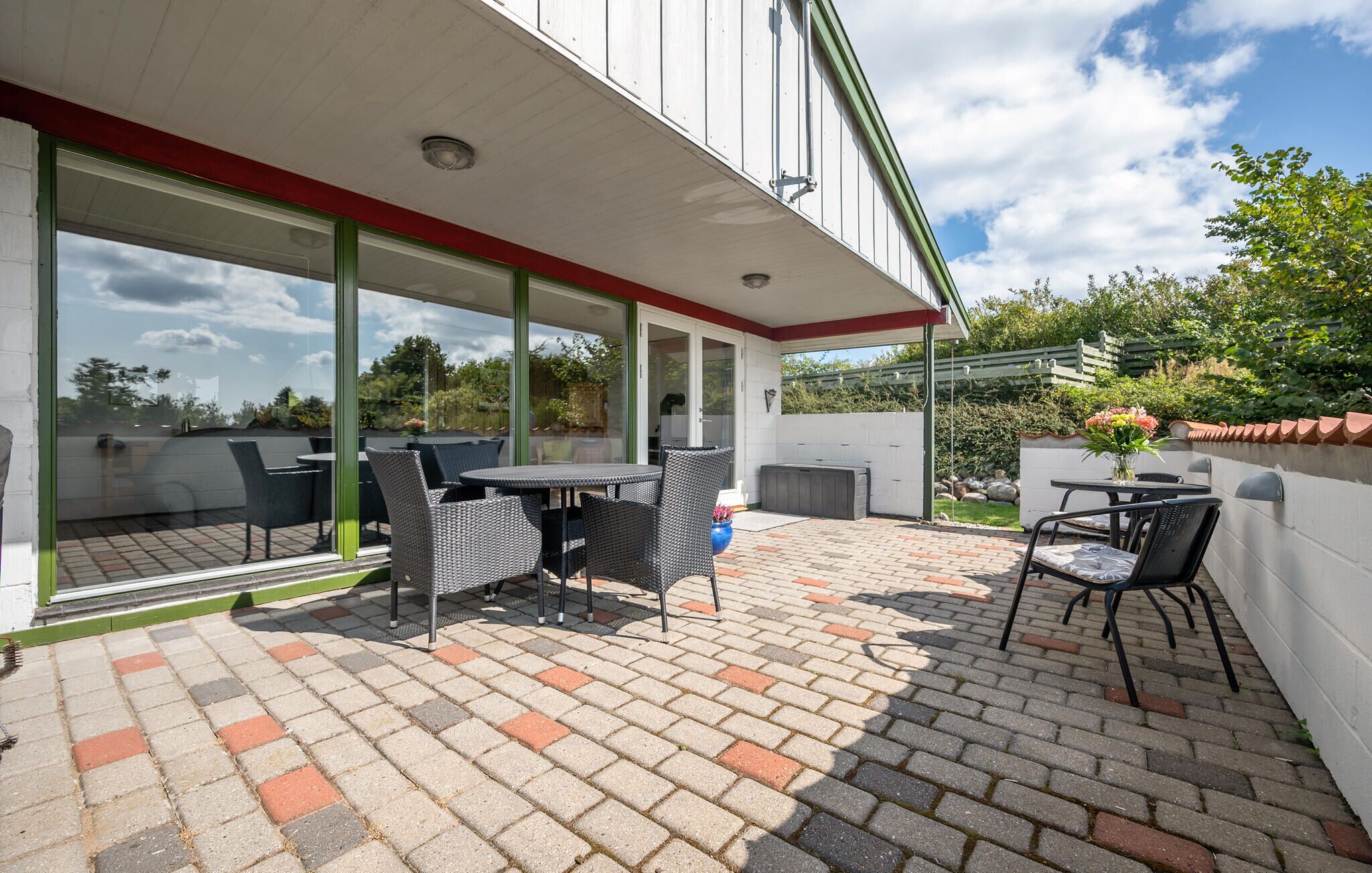 A covered patio with outdoor furniture, a hot tub, and a view of the surrounding landscape.