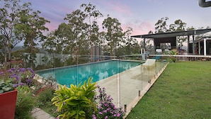 A swimming pool with a glass barrier, surrounded by a grassy area and trees. - The Shed Conversion with Hot tub and amazing views: Building#5 (Austinville)