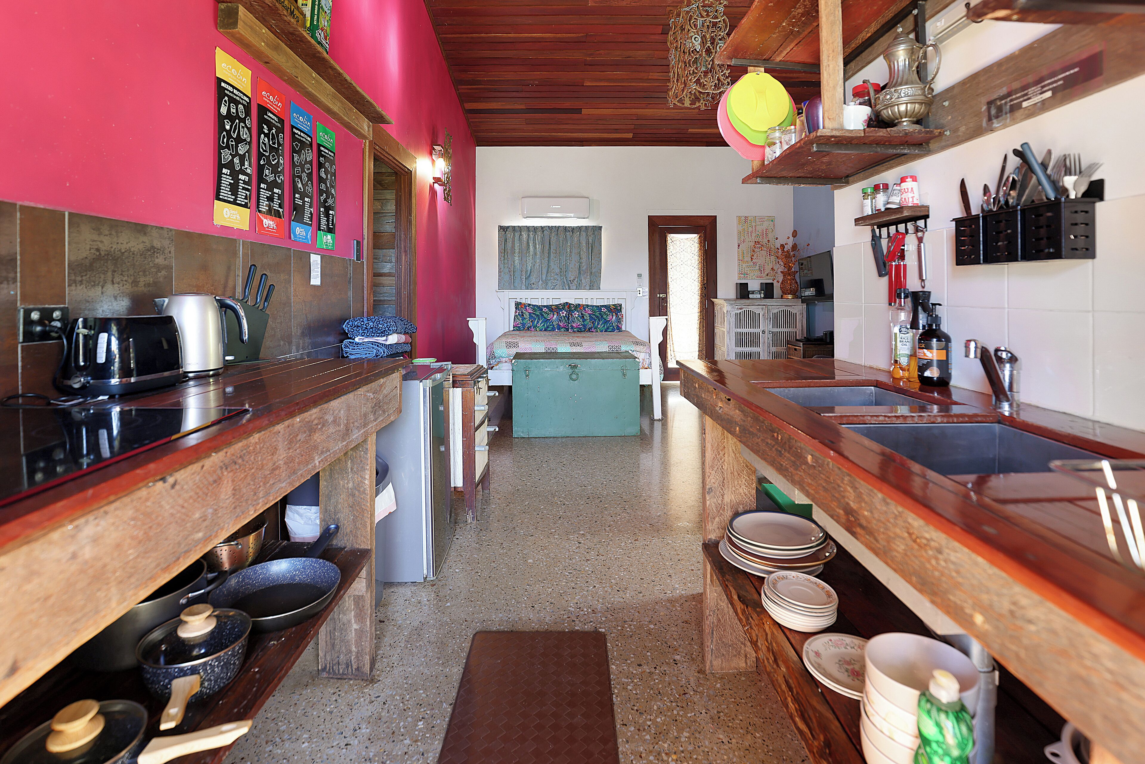 Une cuisine avec des plans de travail en bois, une cuisinière et un évier. On y trouve des placards, un réfrigérateur et une fenêtre avec des rideaux.