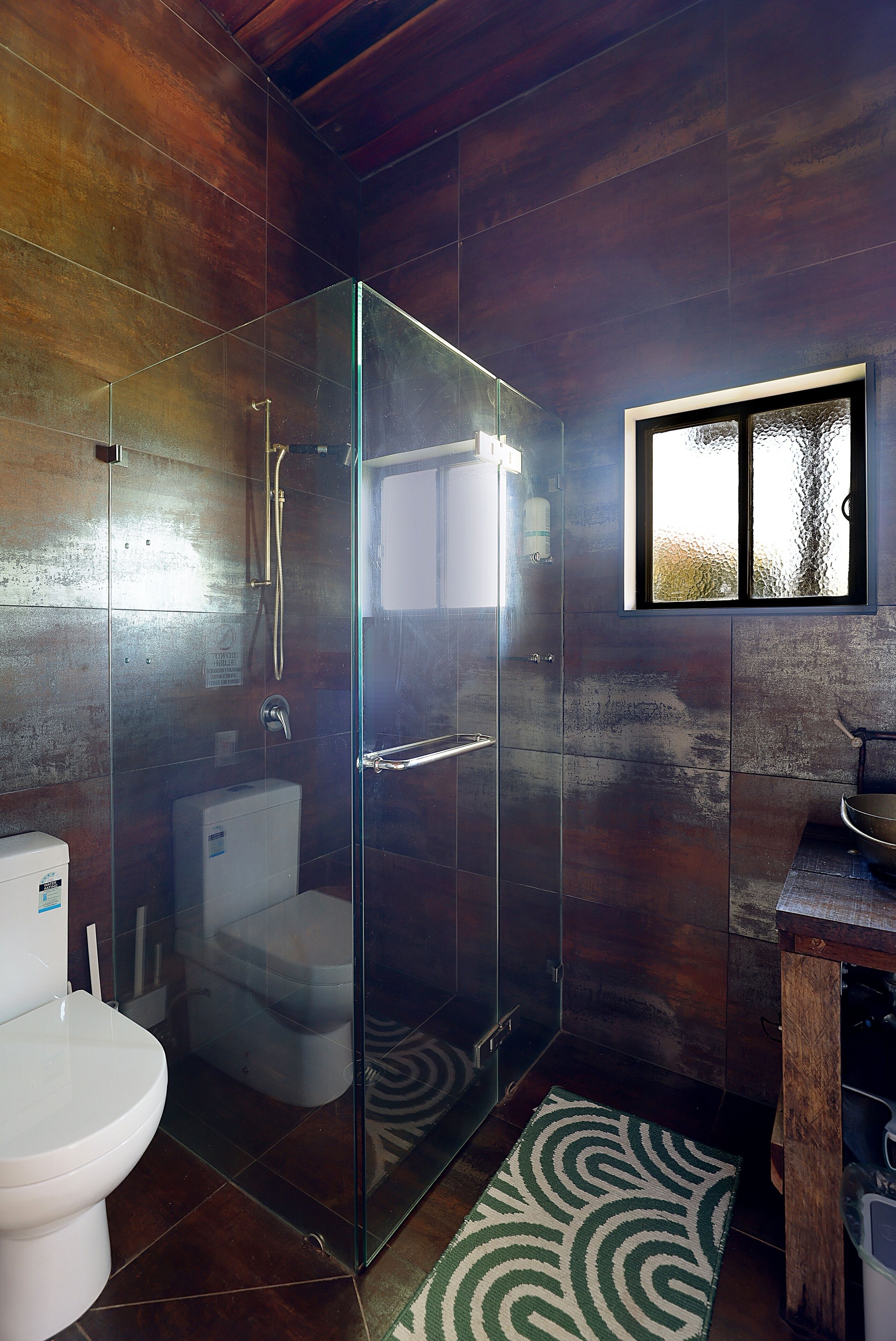 A modern bathroom with a glass-enclosed shower, a toilet, and a sink.