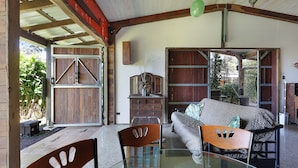 A spacious room with a glass table, wooden chairs, a sofa, and a large wooden door. - The Shed Conversion with Hot tub and amazing views: Building#5 (Austinville)