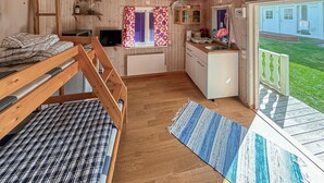 A cozy cabin interior with a bunk bed, kitchenette, and a balcony with a view of the lawn. - Lovely home in Vimmerby with WiFi (Vimmerby)
