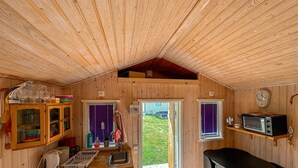 A cabin interior with wooden walls, a kitchen area with a kettle, a sink, and a window with purple blinds. - Lovely home in Vimmerby with WiFi (Vimmerby)