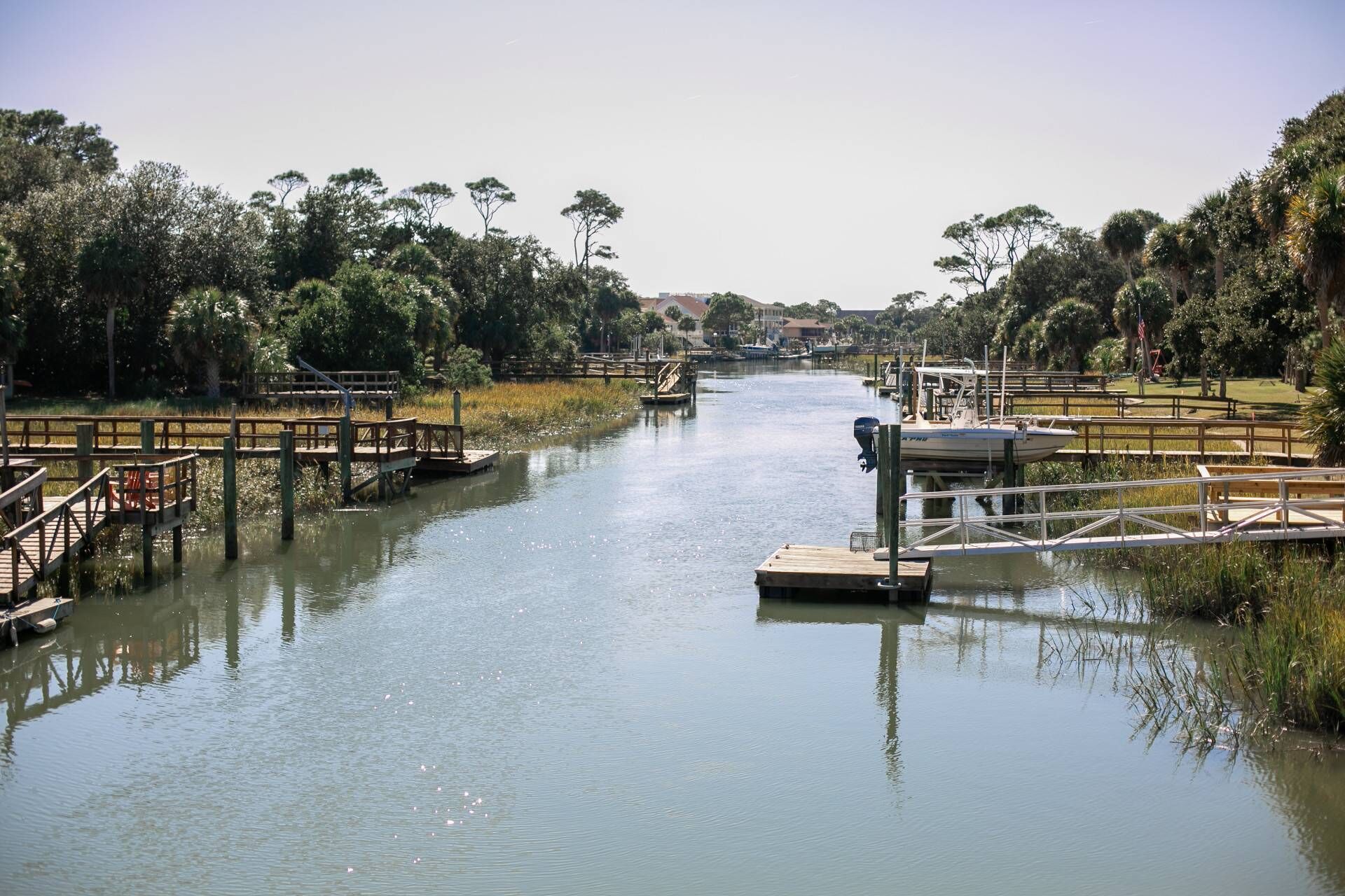 A calm river with wooden docks and a boat docked on the right.