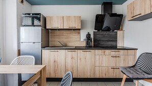 Una cocina compacta con armarios de madera, horno empotrado y cafetera.