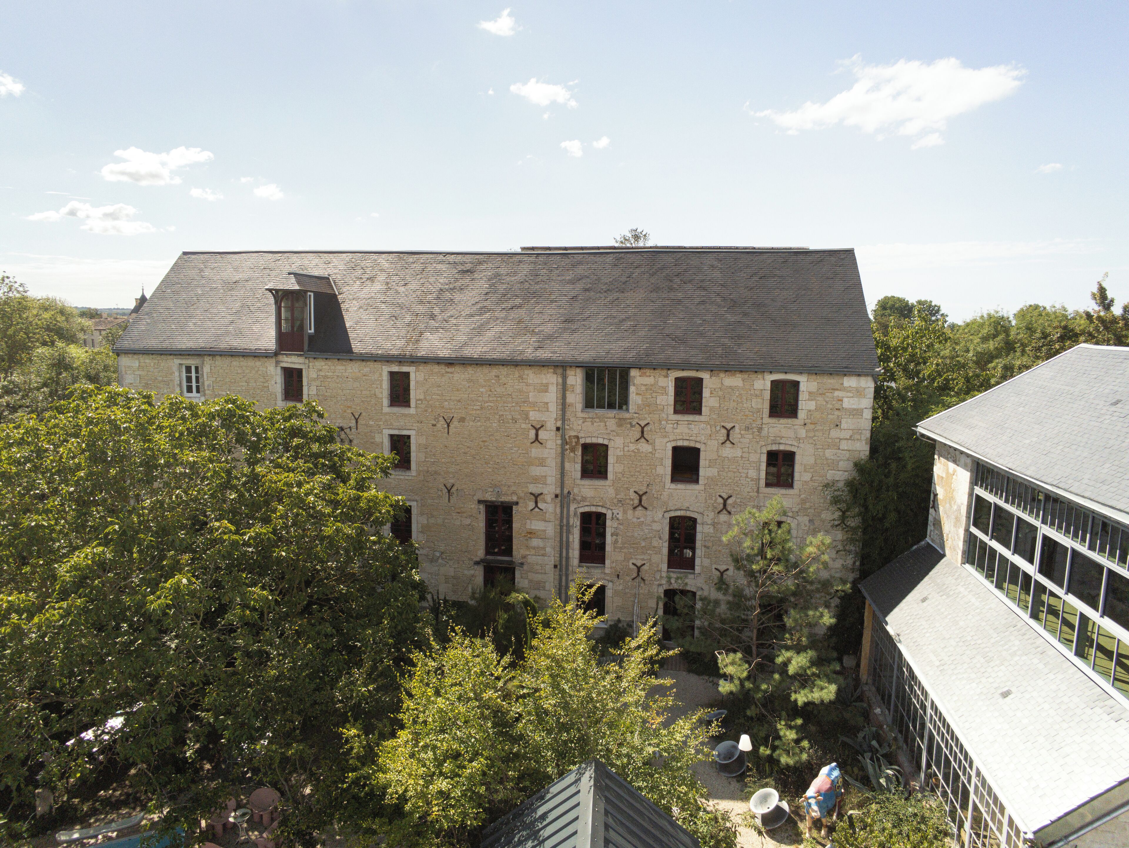 Un bâtiment en pierre doté de nombreuses fenêtres et d’un toit en pente.
