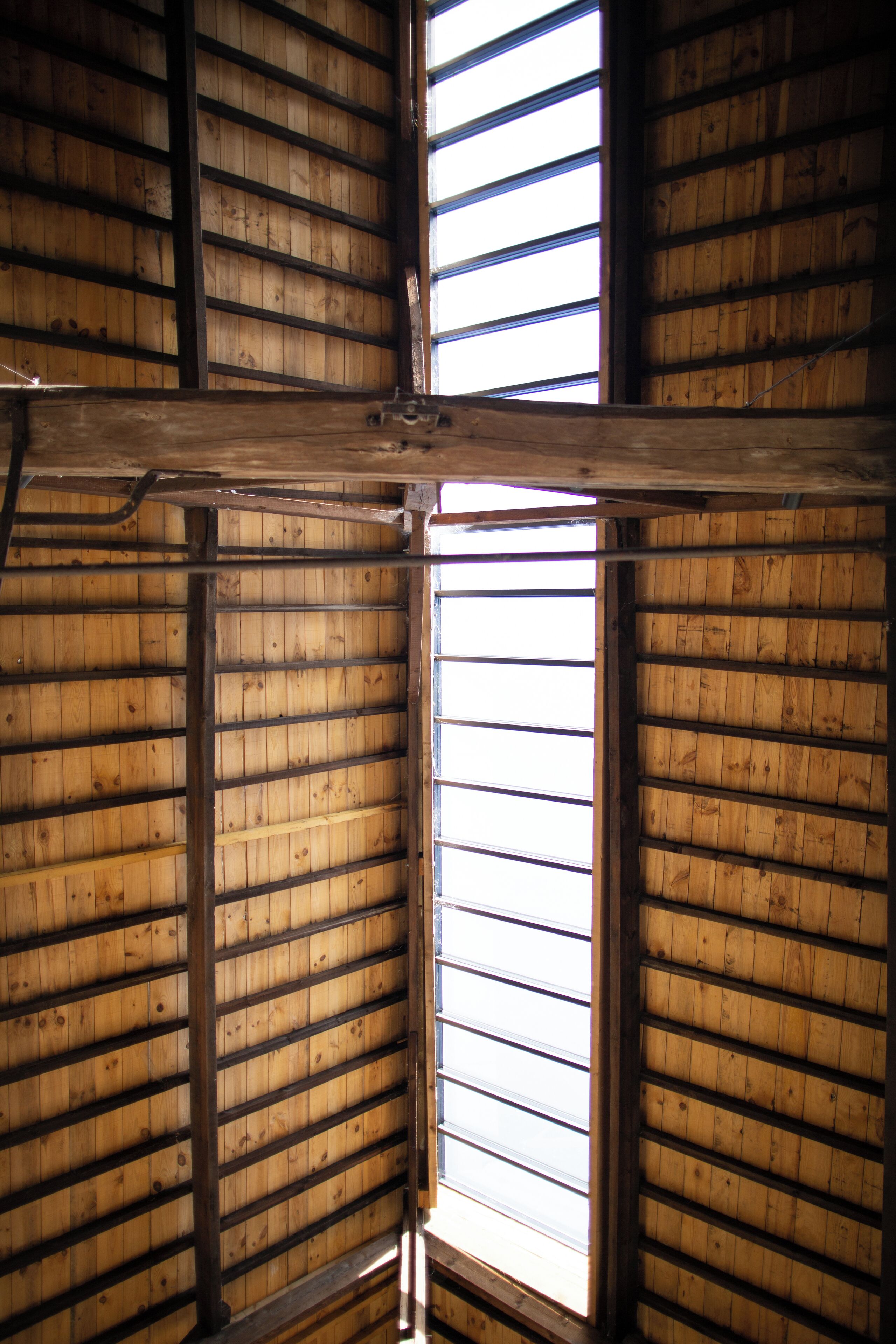 A room with wooden slats on the ceiling and a large window.