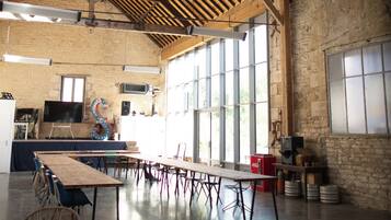 Un vaste hall doté de hauts plafonds, de grandes fenêtres et d’une longue table entourée de chaises.