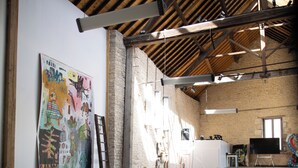 A spacious room with a high ceiling, exposed beams, and a large window allowing natural light. There is a long table with chairs, a whiteboard, and a large abstract painting on the wall. - Former flour mill 20 minutes from La Rochelle: sleeps 15 to 25 (mauzé on the mignon)