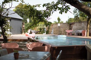 Un cortile con piscina, mobili da esterno e un muro in pietra.