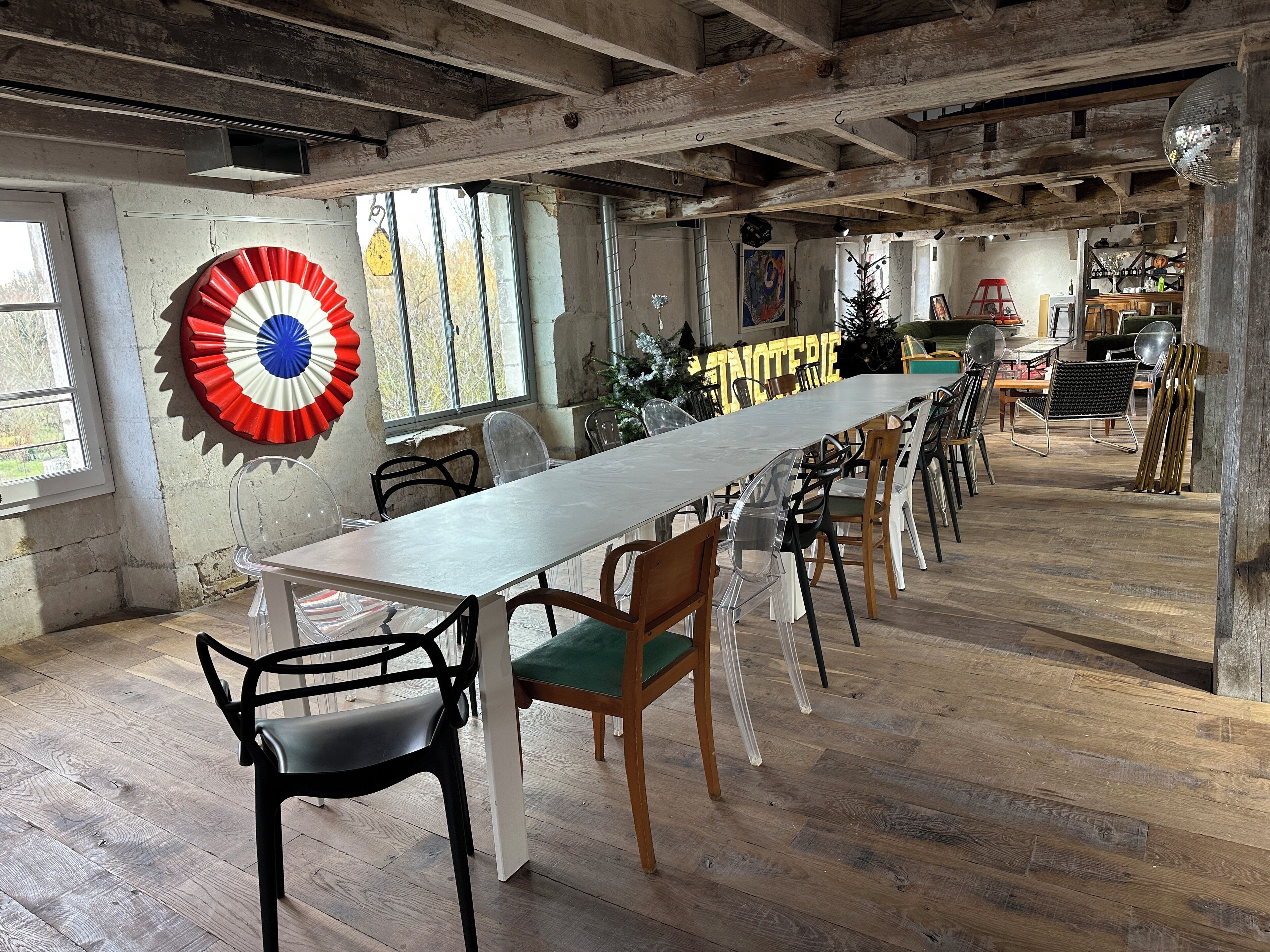 A long dining table with chairs, a large decorative fan, and a wooden ceiling.
