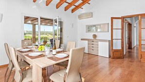 Un comedor con una mesa de madera, sillas color beige y vistas al exterior.