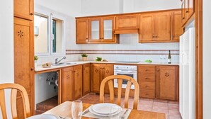 Una cocina con armarios de madera, una mesa de comedor con sillas, un lavamanos y una estufa.