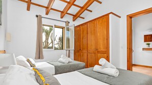 Habitación de hotel con dos camas, armario de madera, ventana grande y techo con vigas de madera.