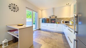 A modern kitchen with a built-in oven, microwave, and refrigerator. - Luxurious home in Risika (Risika)