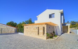 Una casa moderna con fachada de piedra, una pérgola de madera y un camino de entrada pavimentado.
