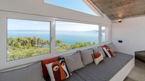 A room with a large window overlooking a scenic view of the sea and greenery. - 5 bedroom beach front home in Blato (Blato)