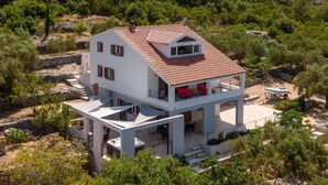 A two-story house with a tiled roof, a balcony with red cushions, and a hot tub on the ground floor. - 5 bedroom beach front home in Blato (Blato)