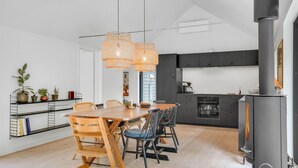 A modern kitchen with a large stove, wooden dining table, and chairs. - Stunning home in Fårevejle with kitchen (Fårevejle)