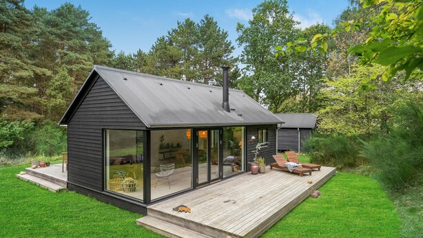 A modern house with a large glass door, a wooden deck, and a garden. - Stunning home in Fårevejle with kitchen (Fårevejle)