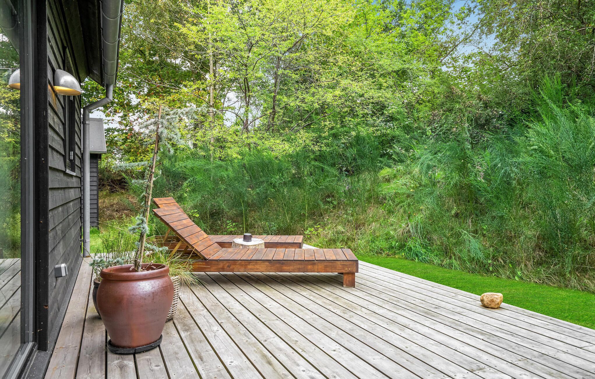 Une terrasse en bois avec un banc intégré et un pot de fleurs.