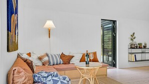 A modern living room with a sofa, a glass table, and a floor lamp. - Stunning home in Fårevejle with kitchen (Fårevejle)