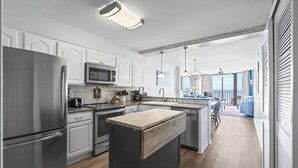 A modern kitchen with stainless steel appliances, a wooden island, and a view to a balcony.