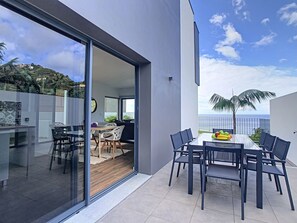 Enjoy a meal al fresco with ocean views from this outdoor dining area, seamlessly connecting to a spacious living room.