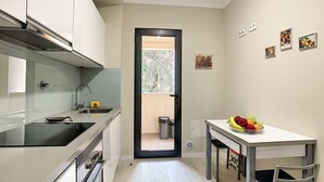 A compact kitchen with a sink, stove, and a small dining area with a fruit bowl. - Apartment Lotus by LovelyStay (Funchal)