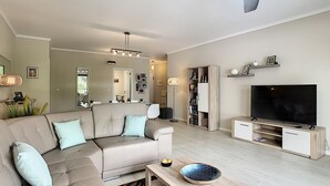 A modern living room with a sofa, TV stand, and a bookshelf. - Apartment Lotus by LovelyStay (Funchal)