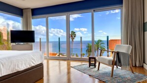 Une chambre d’hôtel avec un grand balcon, un lit, une télévision et une chaise.