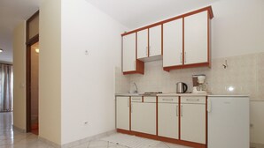 A kitchen with white cabinets, a countertop, and a refrigerator.