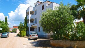 A multi-story residential building with balconies, a parked car, and surrounding greenery. - Apartment 1842/23312 (Istria - Fažana), 50m from the beach (Fažana)