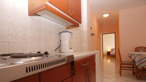 A kitchen with a stove, cabinets, and a coffee maker. There is a dining area with a table and chairs.