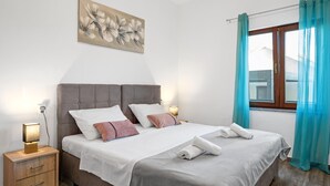 Una camera da letto con un letto, comodini, una lampada, un quadro e una finestra con tende.