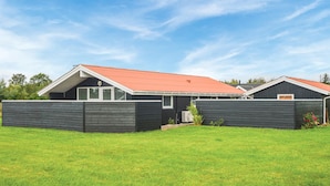A modern building with a red roof and dark siding, surrounded by a well-maintained grassy area. - 3 bedroom cozy home in Hemmet (Hemmet)