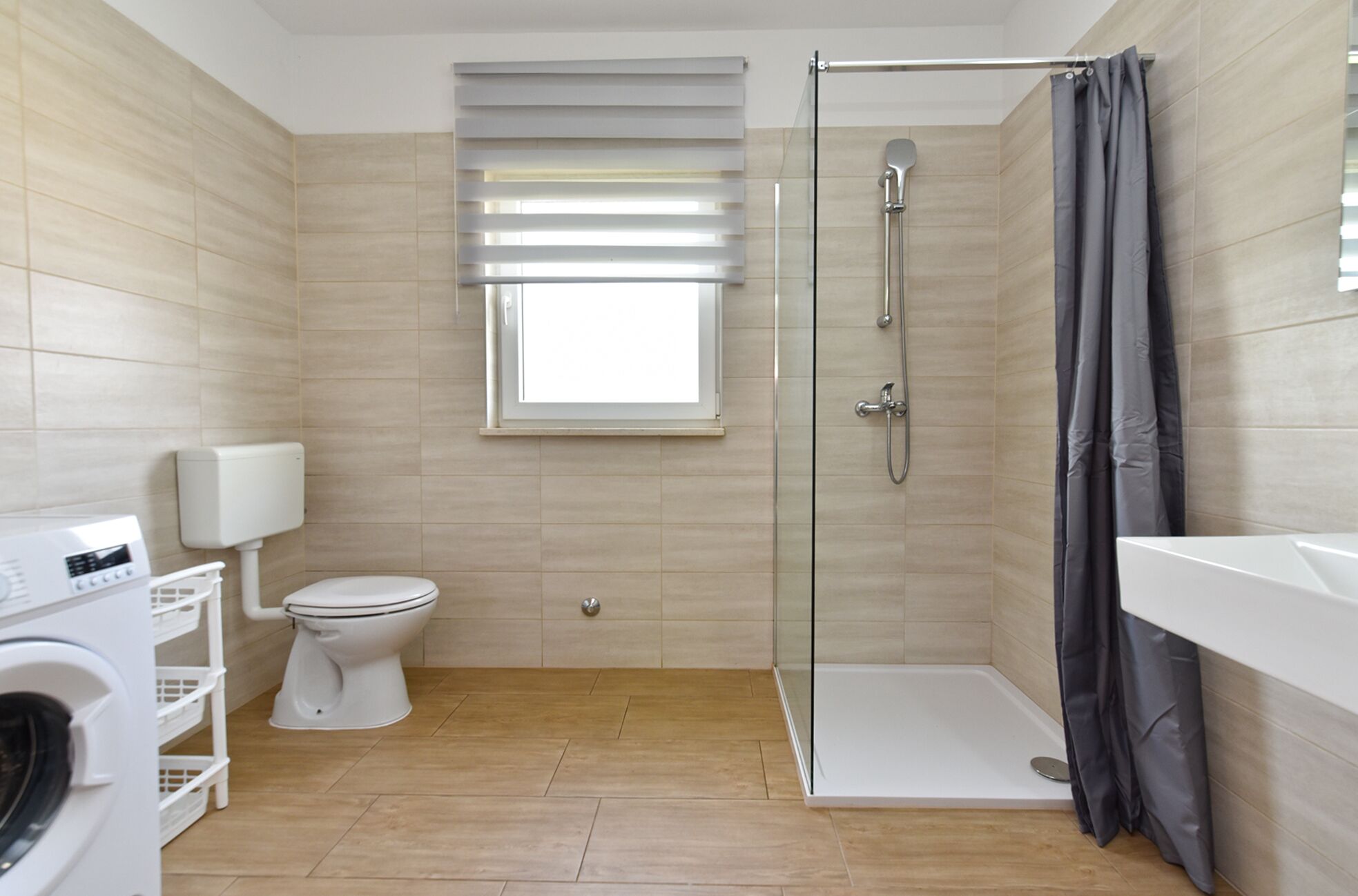 A modern bathroom with a shower, toilet, and washing machine.