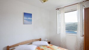 Une chambre à coucher avec un lit en bois, une vue sur un paysage montagneux par la fenêtre et un tableau accroché au mur.