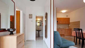 Un salon moderne comprenant un canapé, une table à manger avec des chaises et un coin cuisine doté de meubles en bois.