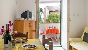A dining area with a table set for two, a bottle of wine, and a glass of wine on the table. There is a television on a wooden cabinet in the background. - Apartment 2024/28736 (Istria - Rabac), 1200m from the beach (Rabac)