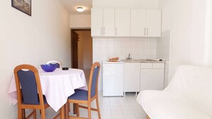 A compact living space with a dining area, kitchenette, and a sofa.