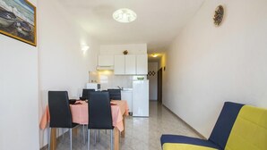 A compact living space with a dining area, kitchenette, and a yellow sofa.