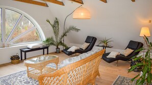 Ein gemütliches Zimmer mit großem Fenster, Korbmöbeln und Deckenventilator.